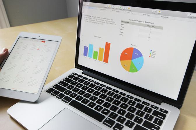 Laptop computer showing colorful bar and pie charts on analytics dashboard