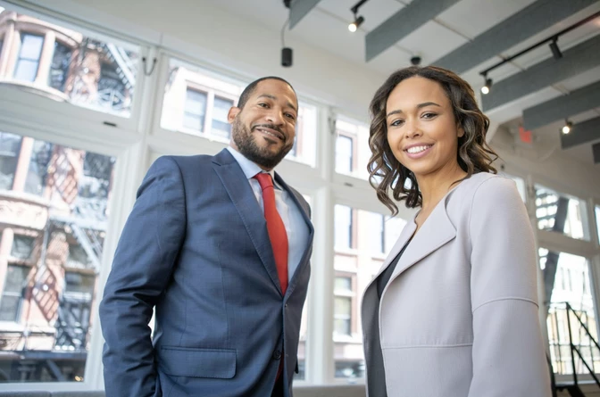 Two business professionals, man in navy suit with red tie and woman in light gray blazer
