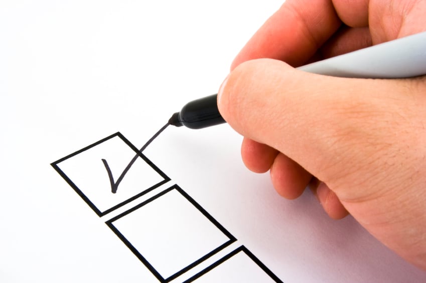 Hand holding black pen marking checkmark in first box of three-item checklist, clean white background, studio product shot