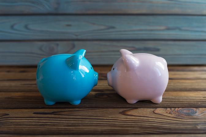 Two glossy ceramic piggy banks side by side on rustic wooden surface—one bright turquoise